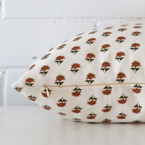 Side angle shot of linen square cushion cover. The terracotta hue and floral style are shown along its seams.