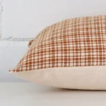 Gingham cushion cover laid on its back side. The image shows a side-on view of the designer material and its rectangle dimensions.