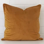 An eye-catching velvet square cushion cover featuring a hue that is honey mustard.