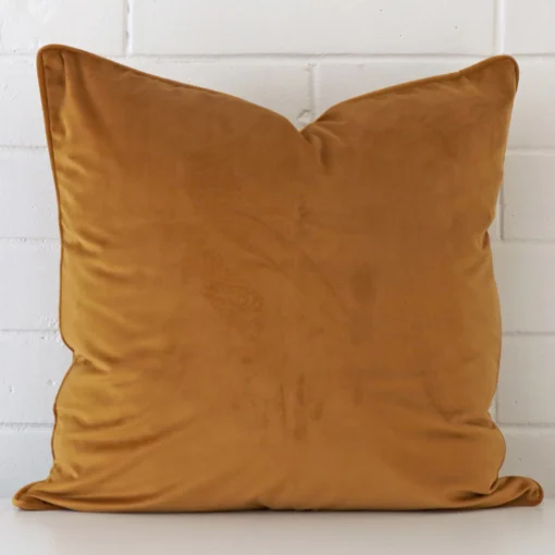 An eye-catching velvet square cushion cover featuring a hue that is honey mustard.