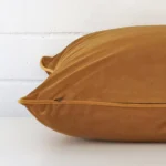 Velvet honey mustard cushion laying on its side. It has a square shape.