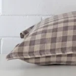 A side view of gingham cushion that has designer fabric and has a square size.