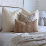 An image showing four designer bed cushions in a white-themed bedroom.