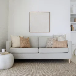 A light grey sofa against a white wall carefully styled with 4 designer cushions of Hunter