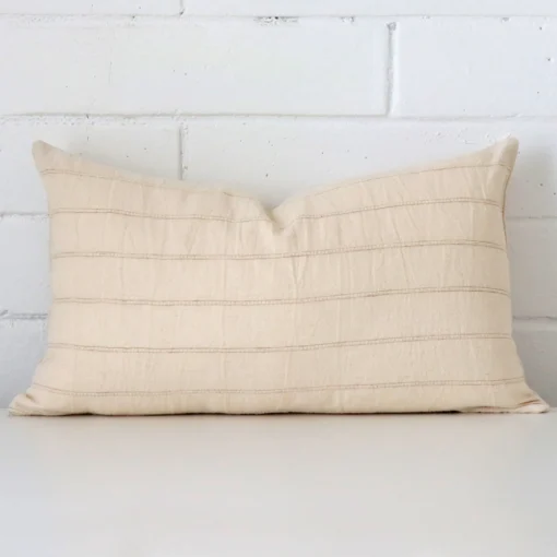 Designer cushion cover features prominently against a white wall. It is a rectangle design and has a striped decorative finish.