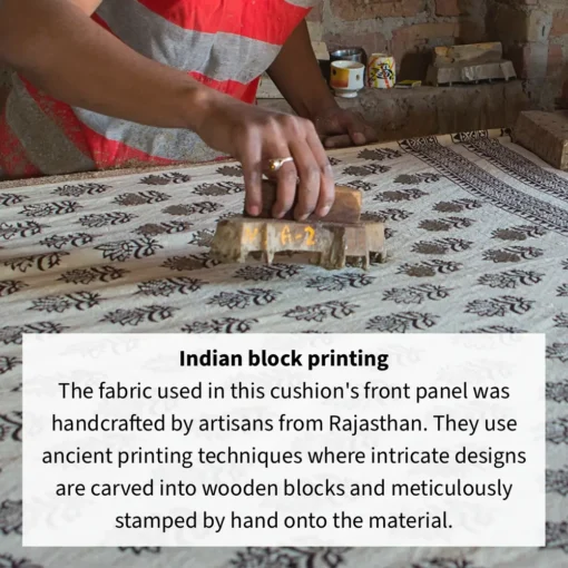 A man using a wooden block to hand print a pattern onto fabric for Indian block printed cushion.