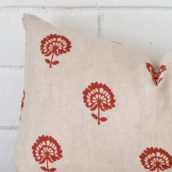 Cropped shot of top left corner of this floral rust cushion cover. This viewpoint shows the linen fabric and rectangle shape with more precision.
