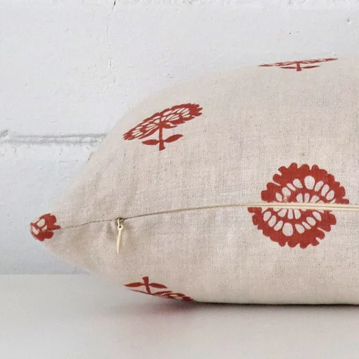 The edge of this linen rectangle cushion in rust is shown. The shot shows the floral design and the front and rear panels.