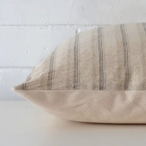 Side perspective showing seam of square cushion cover that has a striped motif on its designer fabric.