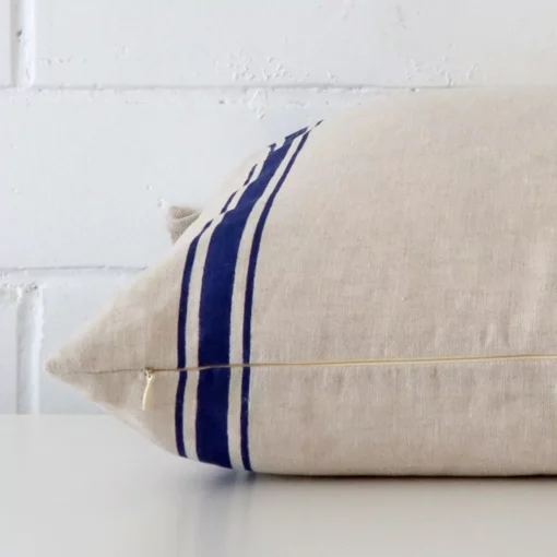 Side perspective showing seam of square blue cushion cover that has a striped motif on its linen fabric