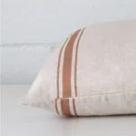 Linen terracotta cushion laying on its side. The striped design and its square size is visible.