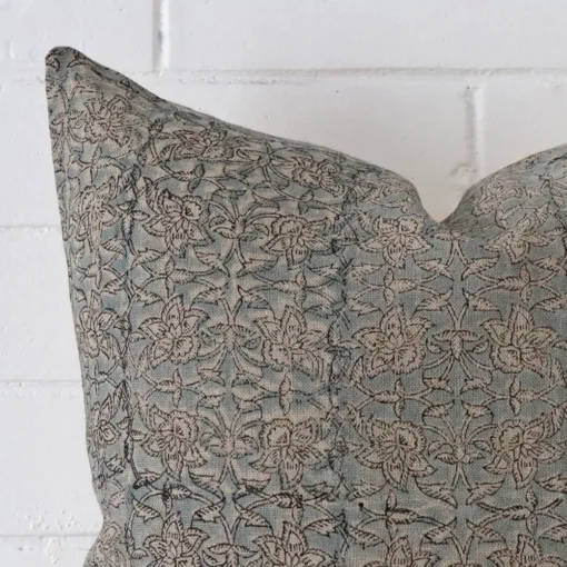 Corner section image showing features of square cushion that has a floral motif on its designer fabric.