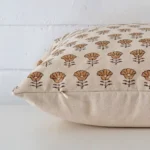 Designer cushion laying on its side. The floral design and its square size are visible.
