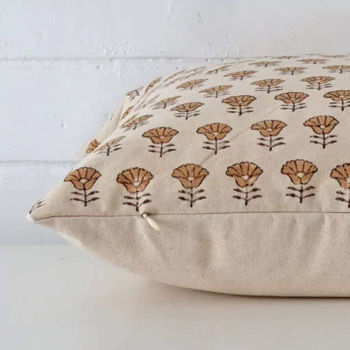 Designer cushion laying on its side. The floral design and its square size are visible.