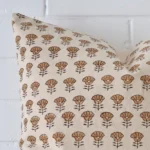 The corner of this designer cushion is shown close up. The finer detail of its square design and floral decorative finish can be seen.