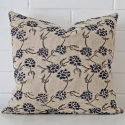 Floral cushion cover sits against a white wall. It is constructed from a superior looking designer material and has square dimensions.