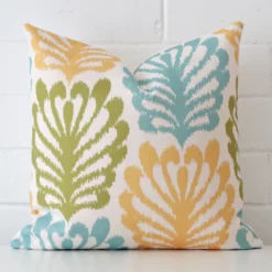 Bold square cushion positioned in front of white brickwork. Its patterned style pops on the linen fabric.