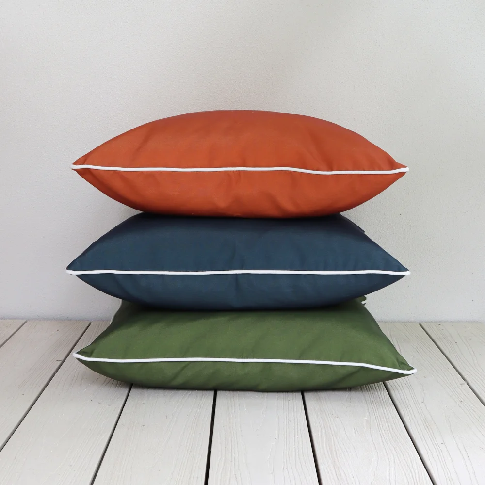 Three large outdoor cushions stacked on top of each other on a timber floor.