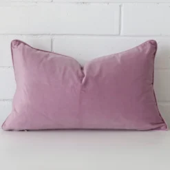 Rectangle cushion cover in lavender colour sitting upright in front of a brick wall. It has been made from a quality velvet material.
