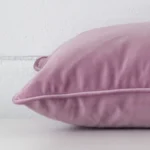 A sideways perspective of this velvet cushion. The positioning shows the border of the rectangle shape and the lavender colour.