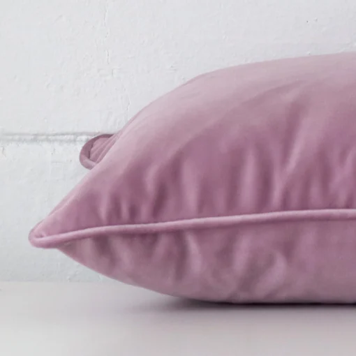 A sideways perspective of this velvet cushion. The positioning shows the border of the rectangle shape and the lavender colour.