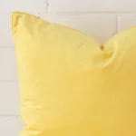 A macro image of the top left corner of this velvet cushion. It is possible to see the finer detail of the square shape and lemon yellow colour.