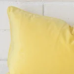 Close range image of lemon yellow cushion. The rectangle size and velvet material can be seen in detail.