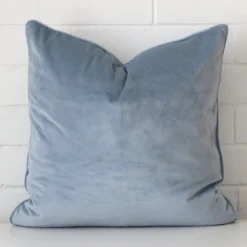 Close up image of velvet square cushion. The image allows you to see the light blue hue more thoroughly.
