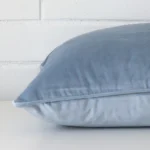Square cushion cover in light blue colour sitting flat. The sideways viewpoint shows the seams of the velvet material.