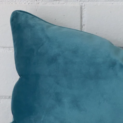 Macro shot showing the top left side of this Rectangle velvet cushion. The light teal hue and design is magnified.