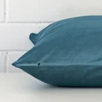Light teal cushion cover laid on its back side. The image shows a side-on view of the velvet material and its square dimensions.