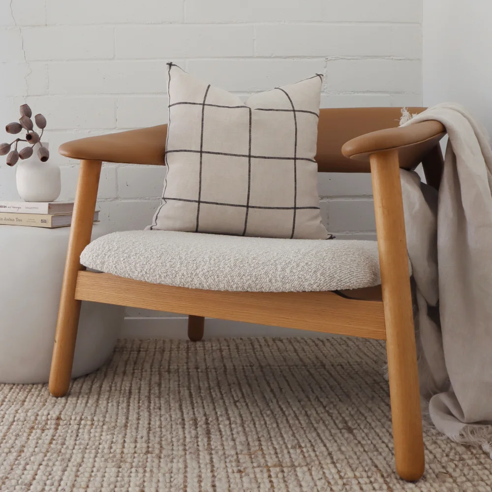 A linen cushion displayed on a fancy wooden seat.