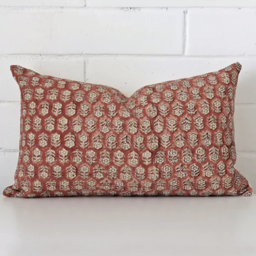Floral cushion cover in front of a white wall. It has a rectangle size and is made from a designer material.