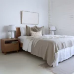 4 designer cushions placed perfectly on a wooden bed between two bedside tables.