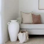 A corner of a grey sofa is styled with the two designer cushions from the Luka sofa cushions set.