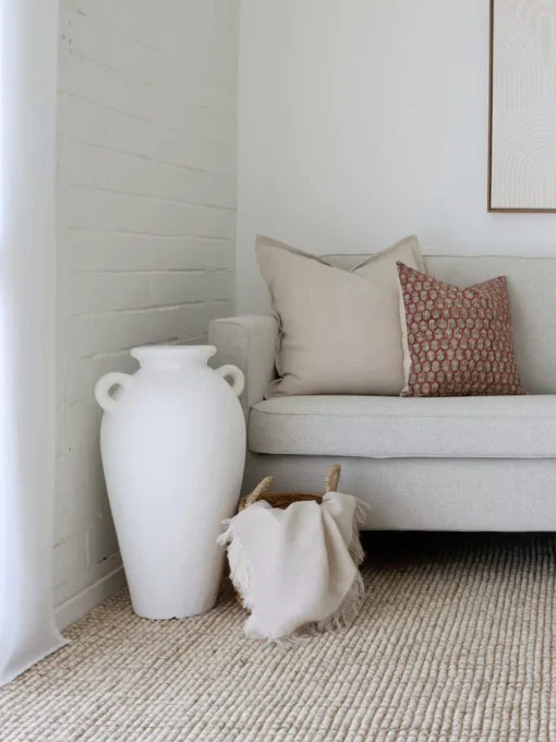 A corner of a grey sofa is styled with the two designer cushions from the Luka sofa cushions set.