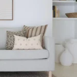 Cushions from the 5 designer cushions for the Luka set are arranged in the corner of an elegant grey sofa.