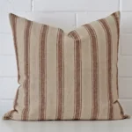 Square striped cushion sitting upright in front of a brick wall. It has been made from a quality designer material.
