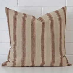 Square striped cushion sitting upright in front of a brick wall. It has been made from a quality designer material.