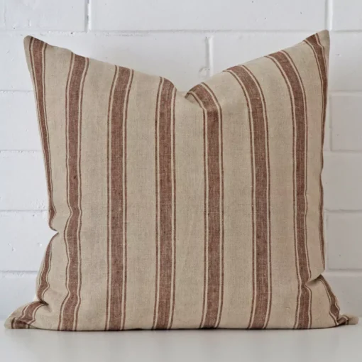 Square striped cushion sitting upright in front of a brick wall. It has been made from a quality designer material.