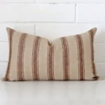 Bold rectangle cushion positioned in front of white brickwork. Its striped style pops on the designer fabric.