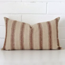 Bold rectangle cushion positioned in front of white brickwork. Its striped style pops on the designer fabric.