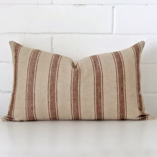 Bold rectangle cushion positioned in front of white brickwork. Its striped style pops on the designer fabric.