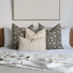 A bed with a wooden headboard adorned with the Mabel bed cushions set showcasing four designer cushions.