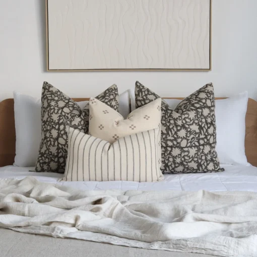 A bed with a wooden headboard adorned with the Mabel bed set showcasing four designer cushions.