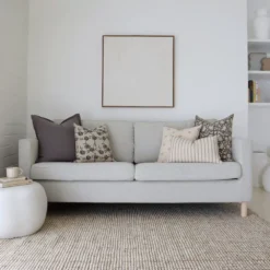 A beautiful combination of 5 designer cushions positioned on light grey sofa.