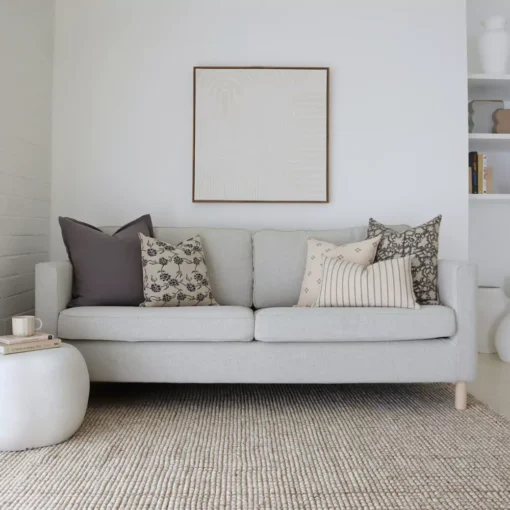 A beautiful combination of 5 designer cushions positioned on light grey sofa.