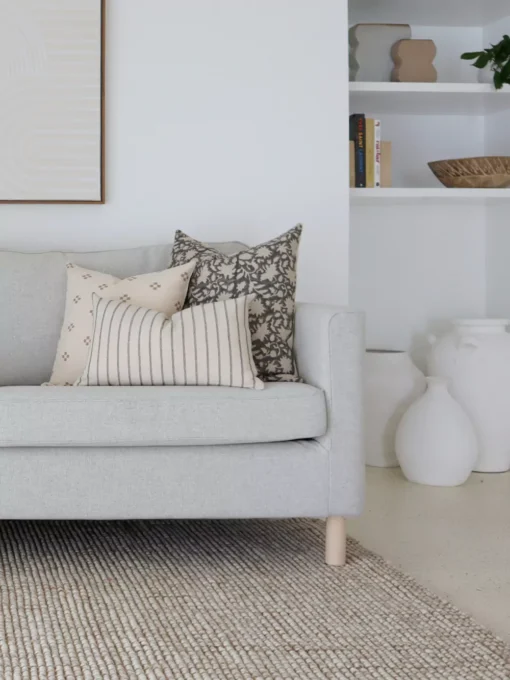 Five designer cushions are neatly arranged on a gray sofa in perfect coordination.