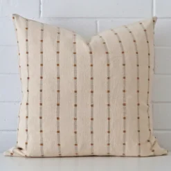 Designer cushion cover features prominently against a white wall. It is a square design and has a striped decorative finish.