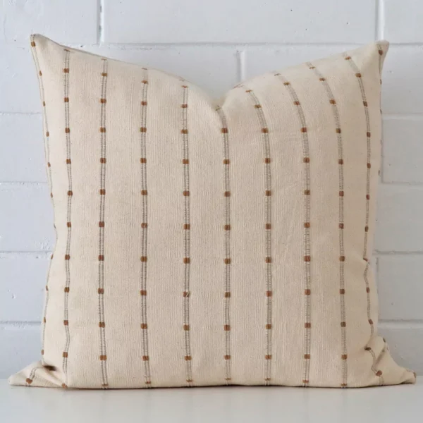 Designer cushion cover features prominently against a white wall. It is a square design and has a striped decorative finish.
